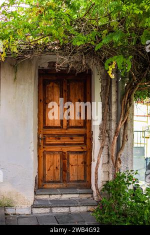 Old wooden door in an old stone wall. Street view of a simple, old-fashioned village house. Old rustic wooden door traditional architectural elements Stock Photo