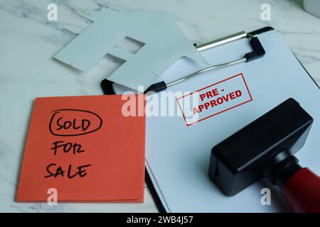 Red Handle Rubber Stamper and Pre-Approved text above paperwork isolated on wooden background Stock Photo