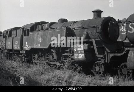 1975, historical, an old steam locomotive, 80098 sitting on a railway track at the Woodham Brothers scrapyard at Barry Docks, South Wales, UK.commonly known as the Barry scrapyard.  Writing on the side says, Cambrian Coast RPA I'm Saved! Please do not remove any more parts from this loco....The Woodham Brothers, scrap metal merchants established in 1892, brought the old Briitsh Railways steam locomotives, stored them and then either sold them on or scrapped them. It is estimated that over 200 steam locomotives were rescued for the railway preservation movement. Stock Photo