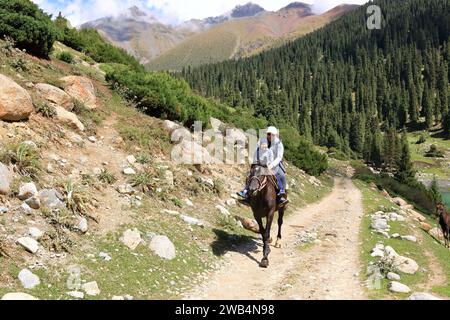 August 31 2023 - Semyonovka, Kyrchyn Valley in Kyrgyzstan: People riding horses in north of Kyrgyzstan mountains Stock Photo