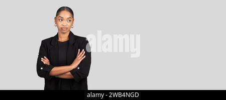 Skeptical African American businesswoman stands with arms crossed Stock Photo