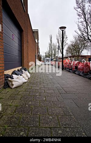 Sandbags for garage and house doors on sidewalk to prevent flooding and water damage. Big bags hold back the high water level after storm in Hoorn NL Stock Photo