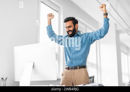 Exuberant indian businessman celebrating success at his computer Stock Photo