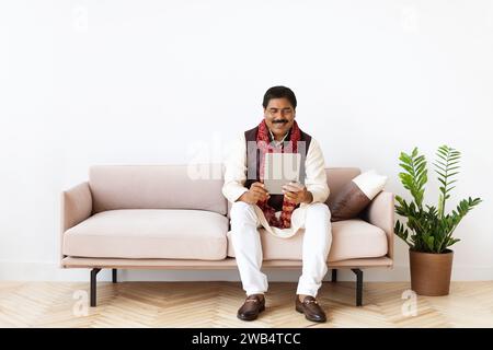 Relaxed mature eastern man chilling at home, using tablet Stock Photo