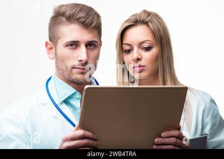 Engaged in their tasks, a male and female doctor use technology to advance patient care Stock Photo