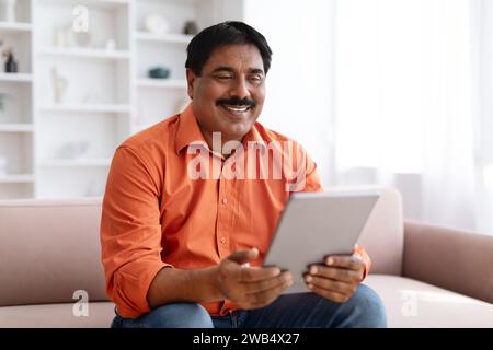 Positive indian man using digital tablet at home Stock Photo