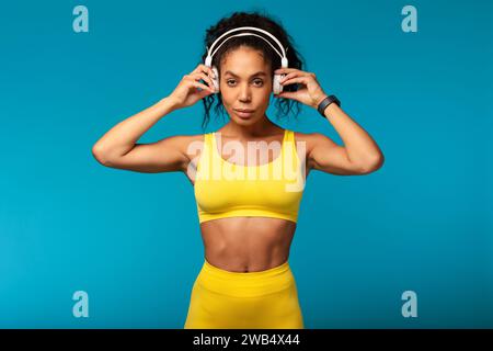 Fit black lady using wireless headphones while training in studio Stock Photo