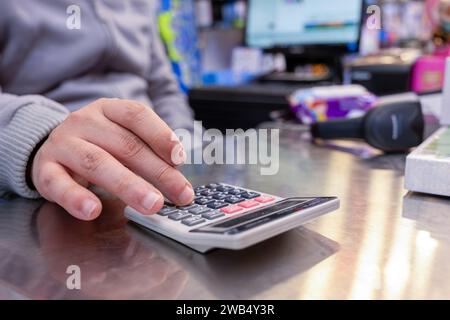 Cashier hands while calculating with barcode scanner and cashier drawer in the background Stock Photo