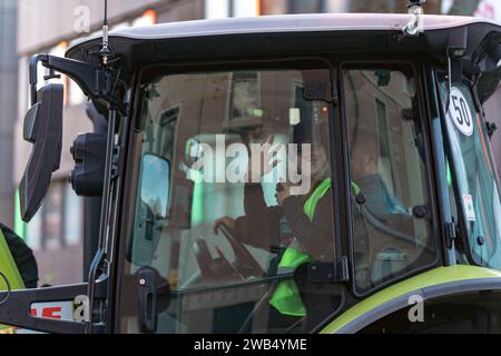 Kaiserslautern, Germany. 8th January, 2024. Closeup of a tractor cabin showing a friendly female protester inside, weaving. German farmers came together in various parts of the country, to protest against government plans to reduce agricultural subsidies. The nationwide protest was initiated by the German Farmers’ Association (DBV) starting on Monday the 8th of January and continuing during the week. The goal is to rise awareness by blocking roads with farm vehicles and showing presence in cities. The demonstrations will result in serious traffic jams in and around various towns. Credit: Gusta Stock Photo