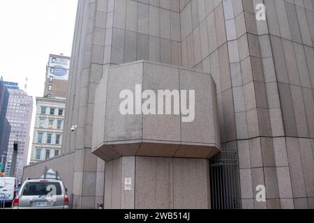 A young adult male is standing on a city sidewalk in front of a tall building Stock Photo