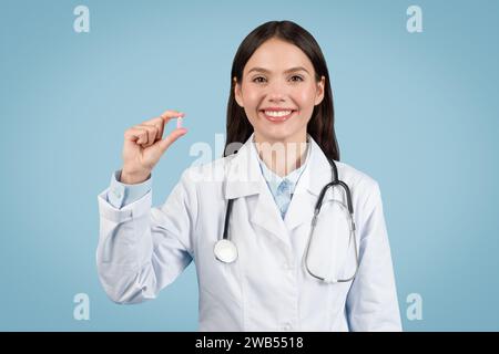 Doctor woman holding pill with confident smile Stock Photo