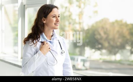Pretty brunette woman young doctor looking through the window Stock Photo