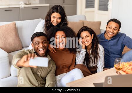 diverse friends taking selfies on mobile phone in living room Stock Photo