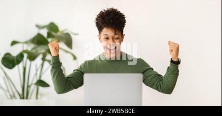 Excited african american guy celebrating success, working at office Stock Photo