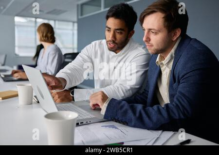 Four focused young multiracial business people in businesswear working on laptops at desk in office Stock Photo