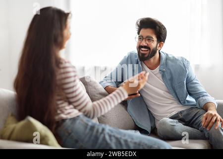 Cheerful young indian couple have conversation, home interior Stock Photo
