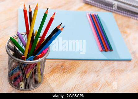 Multicolored wooden pencils on desk with papers and notebooks Stock Photo