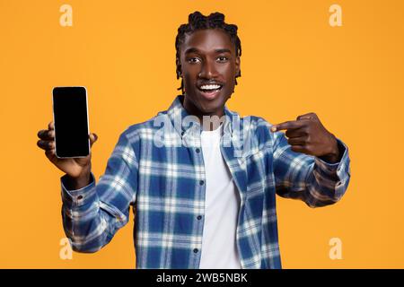 Excited Black Guy Demonstrating Smartphone With Blank Screen At Camera Stock Photo