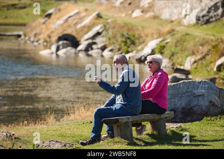 Elderly couple finding solace and joy as they rest on a park bench, engaged in heartfelt conversation, following a rejuvenating strol a testament to Stock Photo