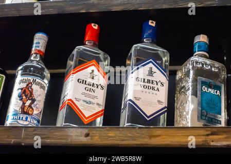 Gilbey's Gin, Gilbey's vodka, Captain Morgan white rum. tequila Olmeca bottles on a bar shelf Stock Photo