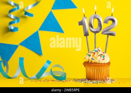 Birthday candle number 102 with cupcake - Yellow background with blue pennants Stock Photo