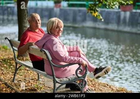 Elderly couple finding solace and joy as they rest on a park bench, engaged in heartfelt conversation, following a rejuvenating strol a testament to Stock Photo