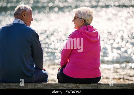 Elderly couple finding solace and joy as they rest on a park bench, engaged in heartfelt conversation, following a rejuvenating strol a testament to Stock Photo