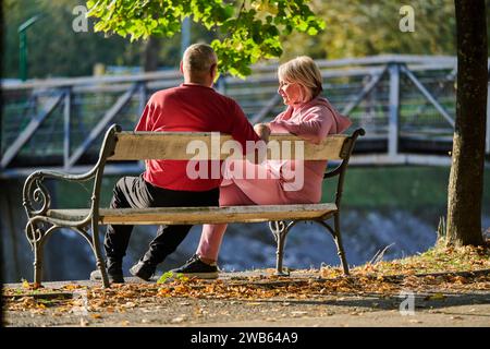 Elderly couple finding solace and joy as they rest on a park bench, engaged in heartfelt conversation, following a rejuvenating strol a testament to Stock Photo