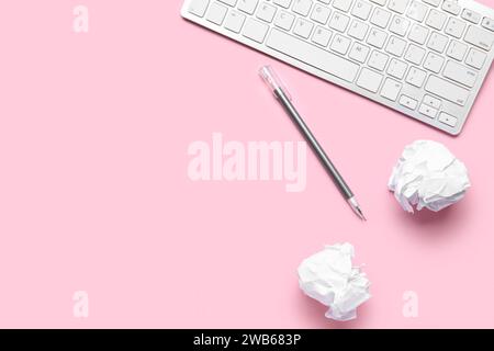 Crumpled paper, pen and keyboard on pink background. World Poetry Day celebration Stock Photo