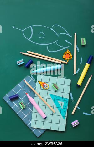 Creative composition with drawn rocket and different stationery on green chalkboard Stock Photo