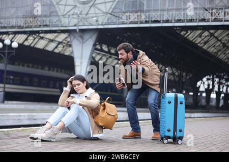 Being late. Worried couple with suitcase waiting at train station Stock Photo