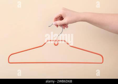Woman holding hanger on beige background, closeup Stock Photo