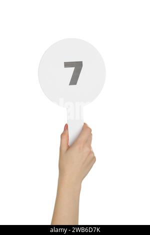 Woman holding auction paddle with number 7 on white background, closeup Stock Photo