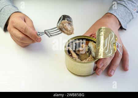 Tin can with ring in male hand. Close up an empty label for design and text. an employee eats canned fish at work Stock Photo