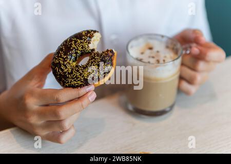 A Chocolate Donut being dipped in a hot coffee Stock Photo