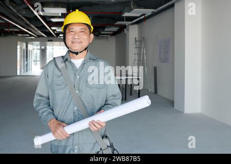 Portrait of smiling builder in hardhat holding blueprint Stock Photo