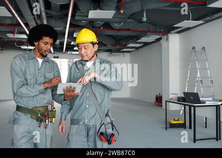 Construction workers discussing details of building plan on digital tablet Stock Photo