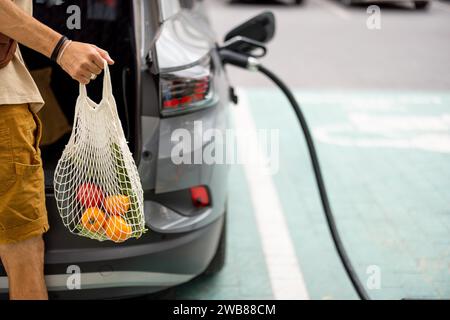 Man charging electric car while shopping Stock Photo