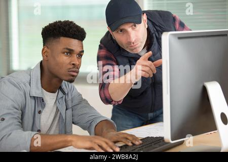 two men conferring while looking at computer screen Stock Photo