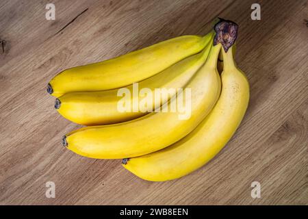 Bananas on a wooden table. a ripe yellow bunch of bananas on the kitchen table. Stock Photo