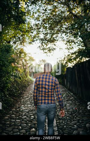 Young man in shirt is walking on a historical castle street with trees Stock Photo