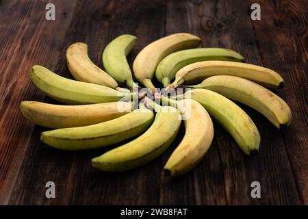 Bananas on brown wooden table top view. Figured position of bananas in geometric shape. bananas are laid out in the shape of the sun. Stock Photo