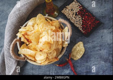 Potato spicy chips in a handmade clay bowl with peppers. Top view. Stock Photo