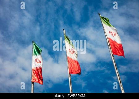 Iranian national flags waving in the wind against blue sky and white clouds. Tehran, Iran. Stock Photo