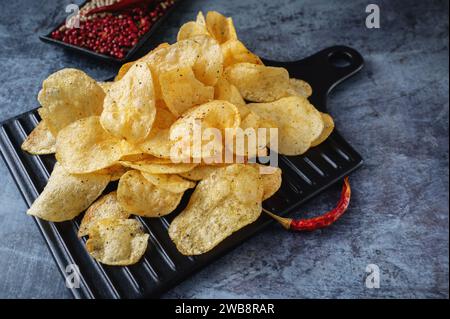 Potato spicy chips in a handmade clay bowl with peppers. Top view. Stock Photo