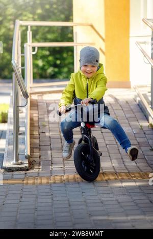 Little boy on a bicycleand downhill acceleration. Caught in motion, on a driveway (motion blurred). The joy of movement. Little athlete learns to keep Stock Photo