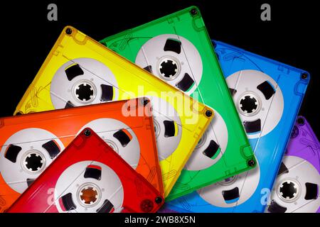 Colored transparent plastic compact audio cassettes lined up in a fan shape on a black background. Bright colors of the LGBT rainbow. The picture is s Stock Photo