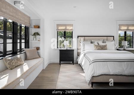 A cozy bedroom interior featuring a double bed situated in front of a large window, next to a comfy armchair Stock Photo