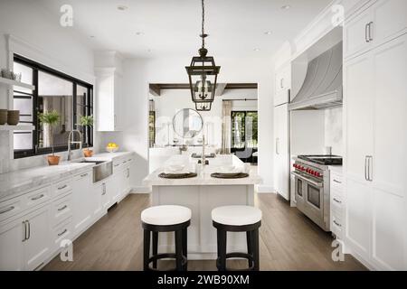 A modern kitchen featuring white cabinets and marble countertops, accented with a sleek black stool for a contemporary look Stock Photo