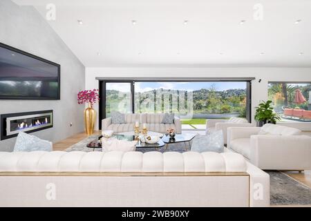 An elegant white sofa in a modern living room, illuminated by natural light from a nearby window Stock Photo